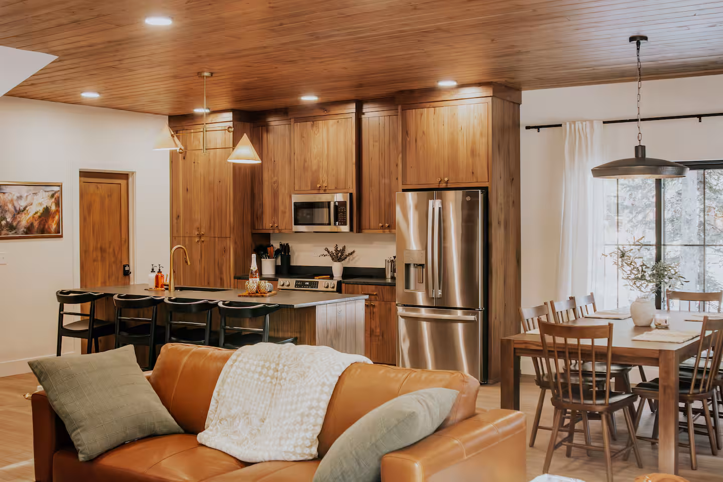 Great room with leather sofa, walnut kitchen and dining beyond